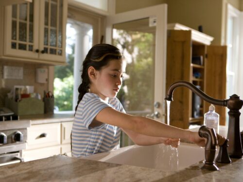 woman in blue and white stripe shirt washing her hands