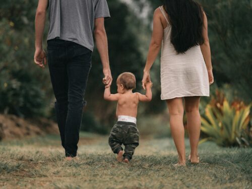 couple walking barefoot with a child at the garden