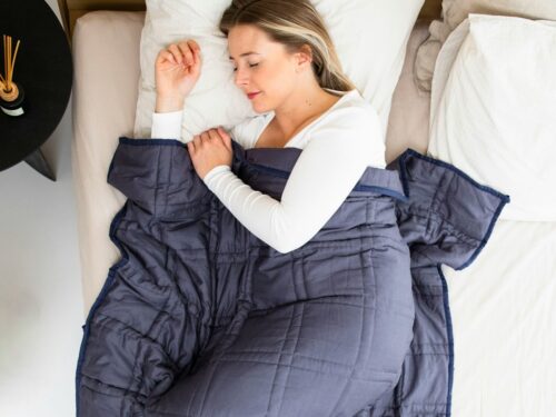 a woman laying in a bed with a blue blanket