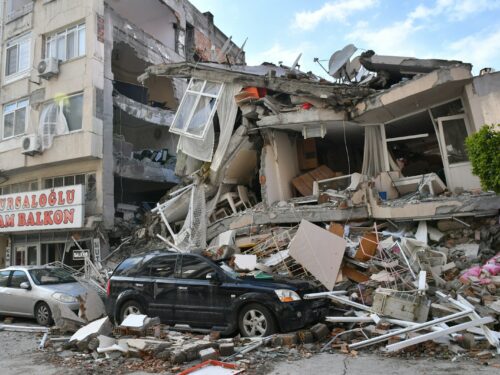 a car is parked in front of a destroyed building