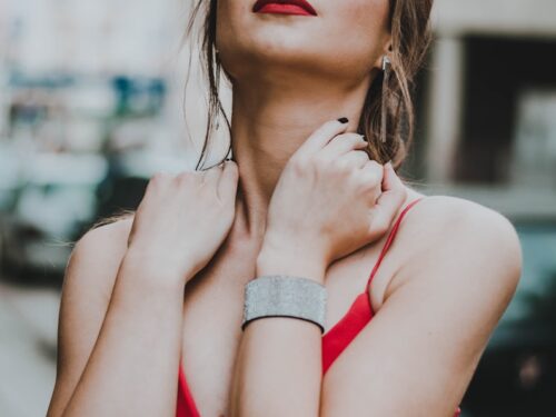 woman holding her neck while closed eyes near building