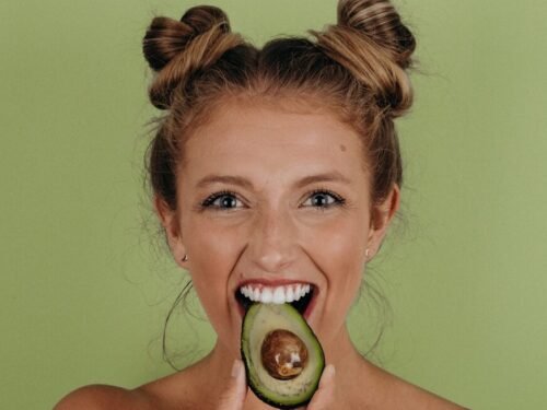 woman holding sliced avocado
