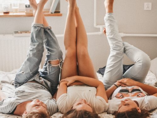 three women lying on bed while raising their feet