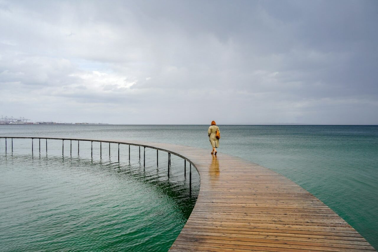 a person walking across a wooden bridge over a body of water