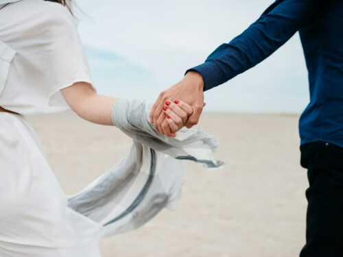 man and woman holding hands together in field during daytime