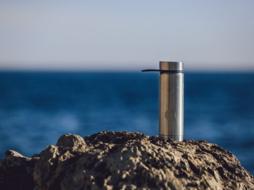 stainless steel tube on brown rock near blue sea during daytime