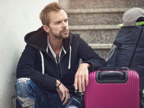 a man sitting next to a purple suitcase