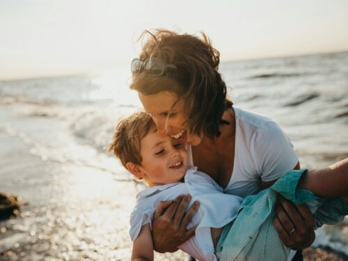 photo of mother and child beside body of water