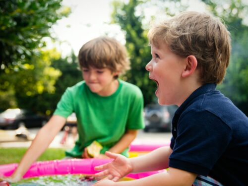 boy in blue shirt screaming near boy in green crew-neck shirt