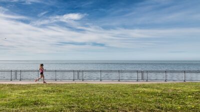 a woman running along a path near the ocean