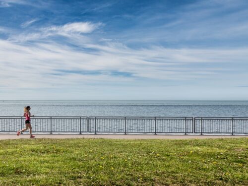 a woman running along a path near the ocean