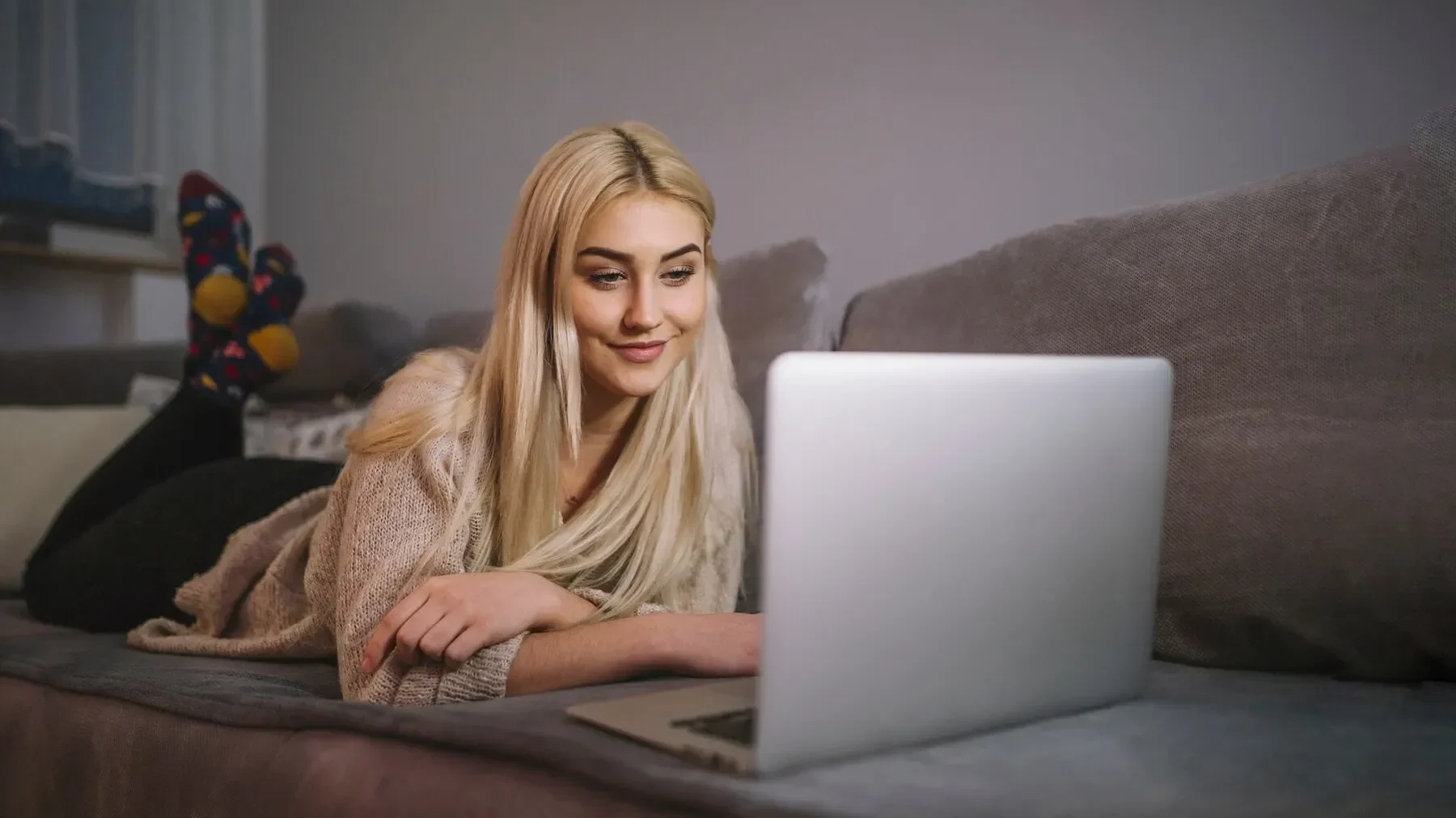Smiling woman browsing laptop couch