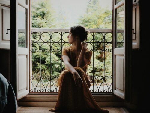 woman sitting on floor near window at daytime