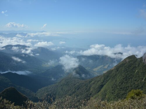 a view of the mountains and clouds from the top of a hill