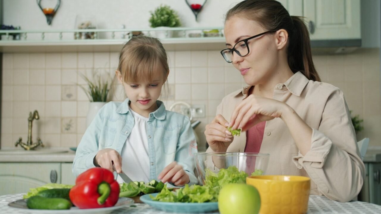 Mother and daughter preparing salad in kitchen.