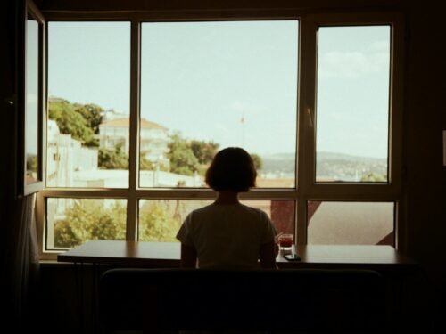 A person sitting at a table looking out a window