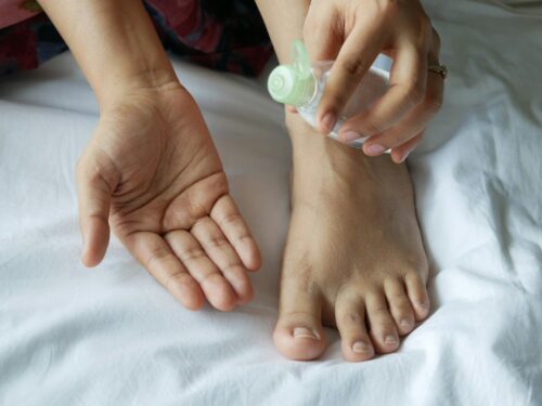 a person with a bottle on their foot on a bed