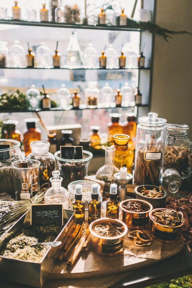 Glass jars and copper containers filled with dried herbs and spices on a table