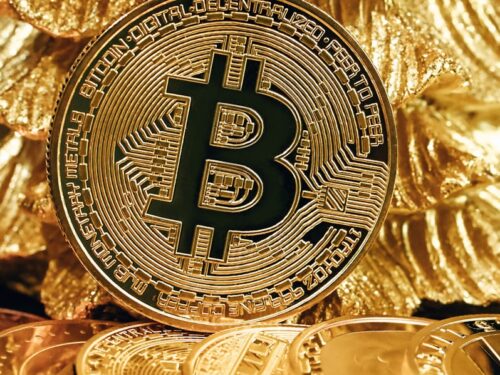 a bitcoin sitting on top of a pile of gold coins