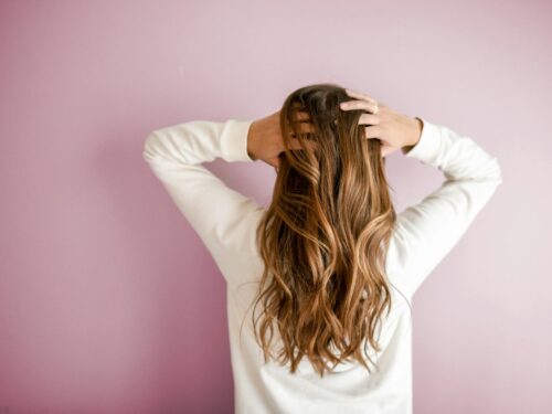 woman in white long-sleeved shirt standing in front of pink wall