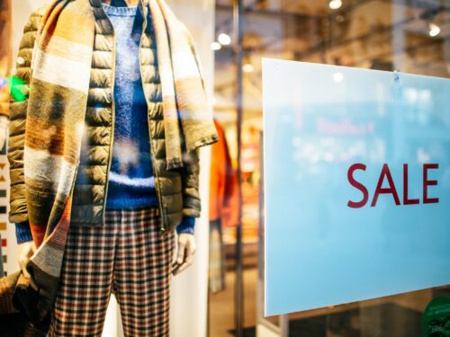 a mannequin in a window display with a sale sign