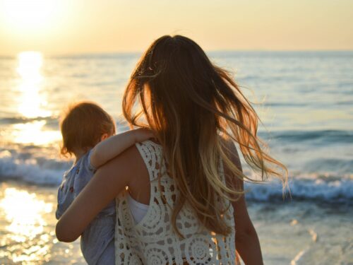 woman in white tank top carrying child in blue shirt