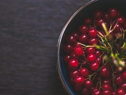 a metal bowl filled with red berries on top of a wooden table