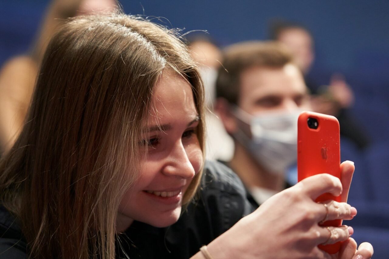 woman in black shirt holding red smartphone